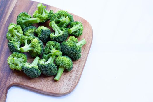 Fresh green broccoli on wooden cutting board on white background.