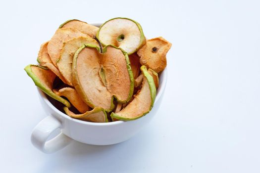 Dried apple slices in white cup on white background.