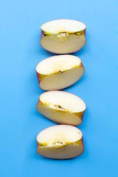 Ripe apple slices on blue background.