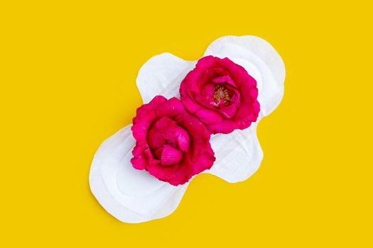 White sanitary napkin with red roses on yellow background. Copy space