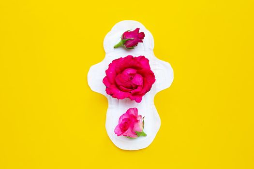 White sanitary napkin with red roses on yellow background. Copy space