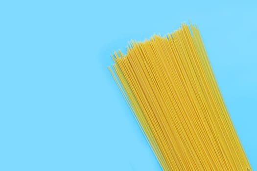 Yellow long spaghetti on blue background. Copy space