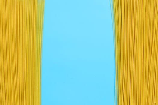 Yellow long spaghetti on blue background. Copy space