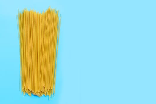 Yellow long spaghetti on blue background. Copy space