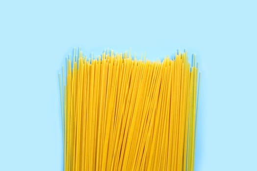 Yellow long spaghetti on blue background. Copy space