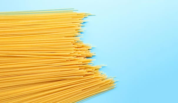 Yellow long spaghetti on blue background. Copy space