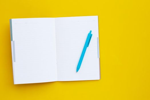 Notebook with pen on yellow background.