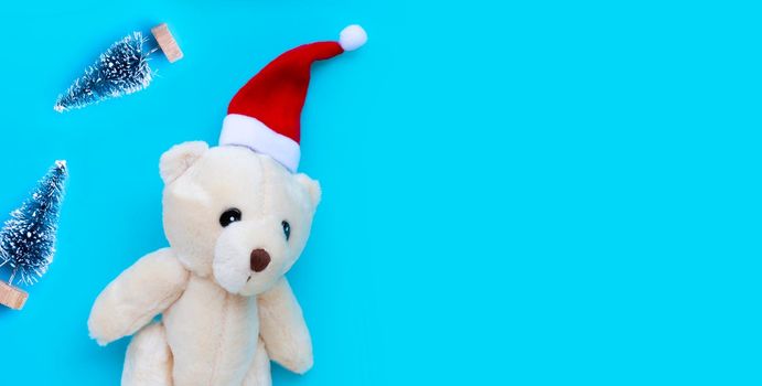 Toy bear wearing a santa hat on blue background. Christmas holidays concept