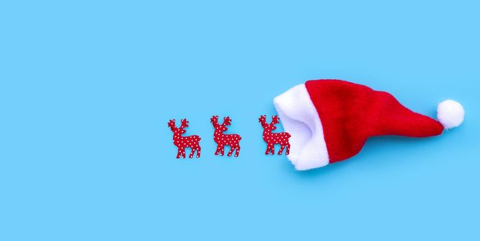 Santa hat with reindeers on blue background. Copy space