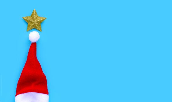 Golden star with santa hat on blue background. Copy space