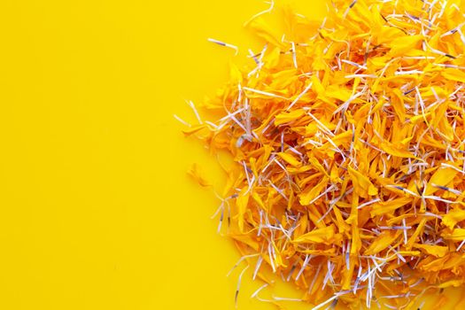 Petals of marigold flower on yellow background.
