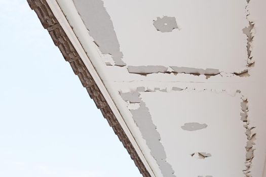 White color paint peeling off on ceiling house. Under the roof