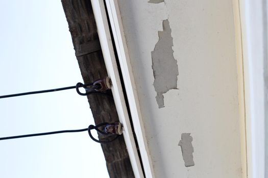 White color paint peeling off on ceiling house. Under the roof
