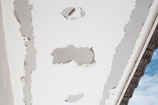 White color paint peeling off on ceiling house. Under the roof