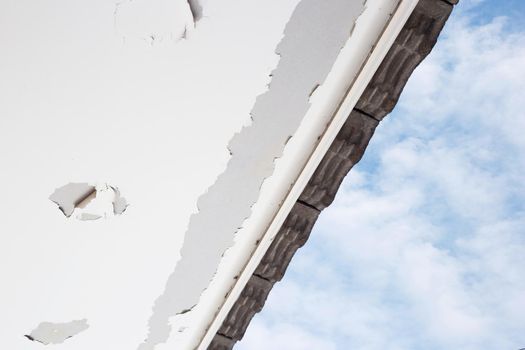 White color paint peeling off on ceiling house. Under the roof