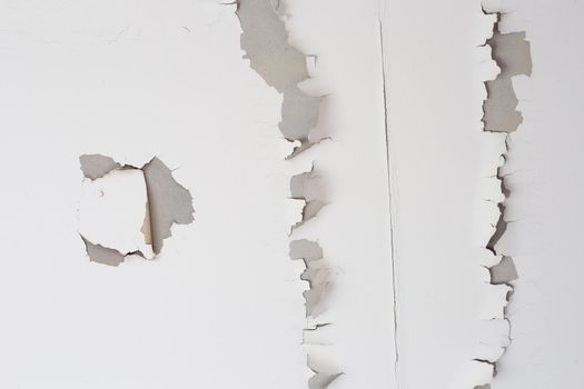 White color paint peeling off on ceiling house. Under the roof