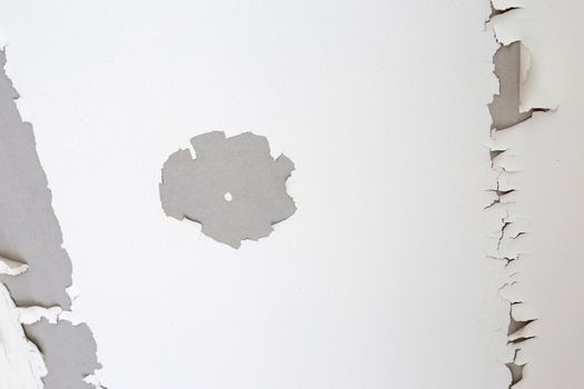 White color paint peeling off on ceiling house. Under the roof