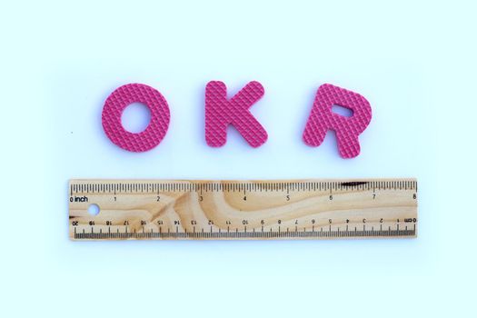 OKR alphabet with wooden ruler on white background.