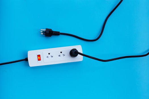 Electrical power strip and plug on blue background. Top view
