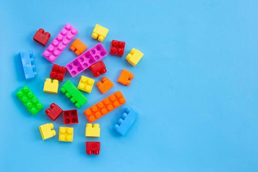Plastic building blocks on blue background.