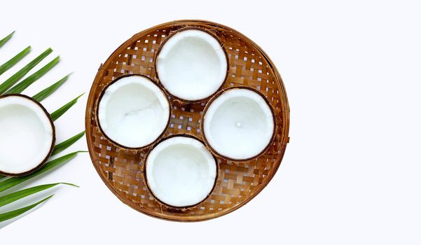 Half coconuts on wooden bamboo threshing basket on white background. Copy space