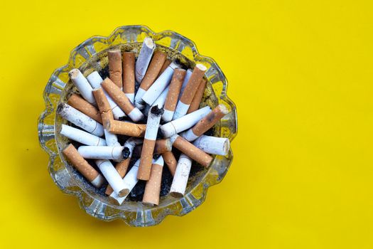 Smoked cigarettes on yellow background. Copy space