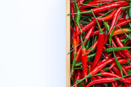 Hot chili peppers in wooden box on white background. Top view