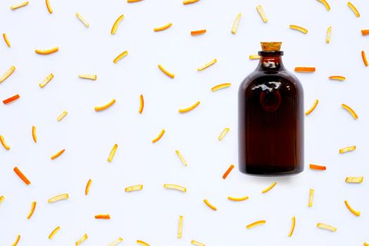 Essential oil bottle with orange peels on white background. top view