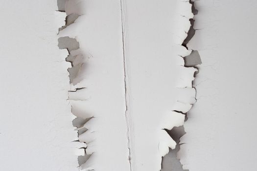 White color paint peeling off on ceiling house. Under the roof