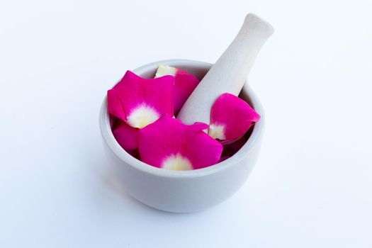 Rose petals in porcelain mortar with pestle isolated on white background.