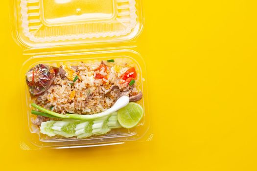 Fried rice in plastic box on yellow background.