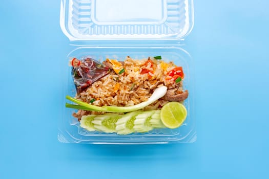 Fried rice in plastic box on blue background.