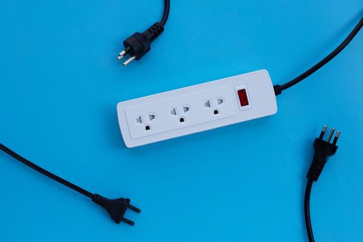 Electrical power strip and plug on blue background. Top view