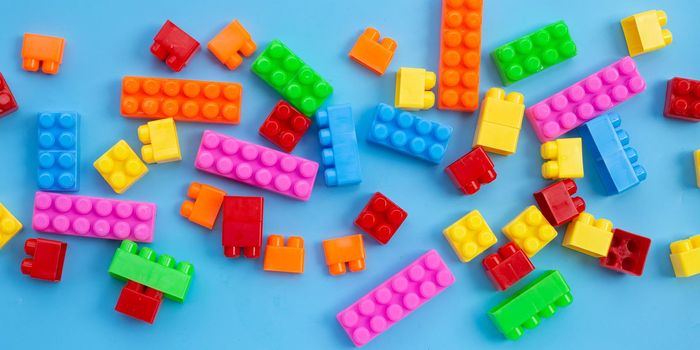 Plastic building blocks on blue background.