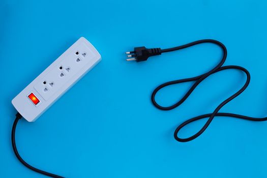 Electrical power strip and plug on blue background. Top view