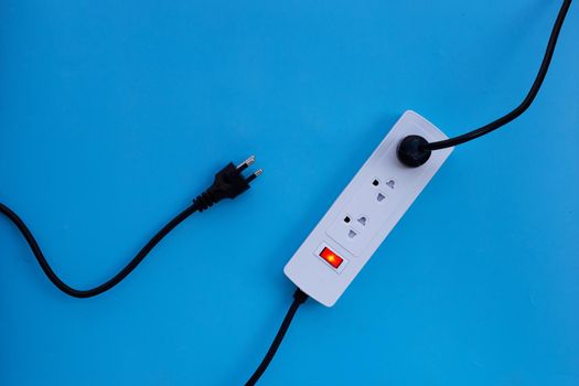Electrical power strip and plug on blue background. Top view