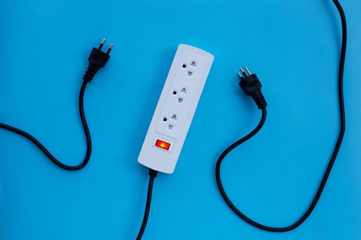 Electrical power strip and plug on blue background. Top view