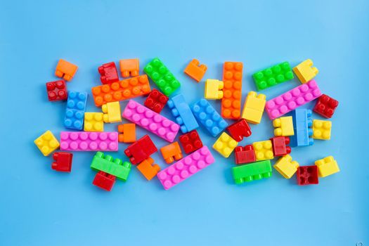 Plastic building blocks on blue background.
