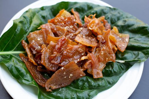 Sweet pork or pork Jerky on noni or morinda citrifolia leaf. Dark background.