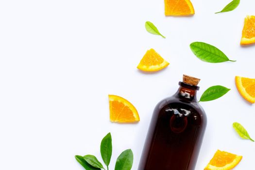 Fresh orange fruit with essential oil bottle on white background.