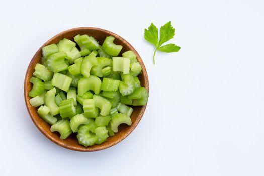 Fresh celery slices in wooden bowl on white background. Copy space