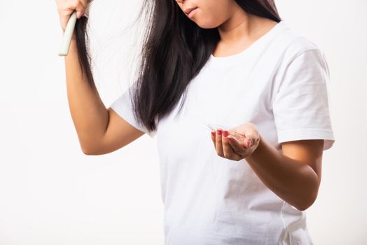 Asian woman weak hair problem her use comb hairbrush brush her hair and showing damaged long loss hair from the brush on hand, studio shot isolated on white background, Medicine health care concept