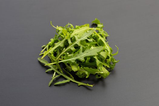 Fresh green rocket salad on dark background.