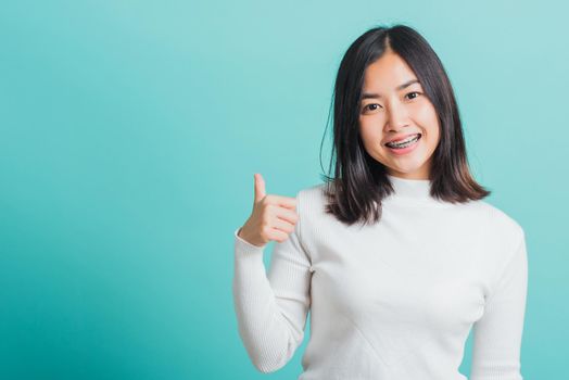 Young beautiful Asian woman cheerful smiling showing finger thumb up, Portrait happy female using showing like the gesture for good sign, studio shot isolated on a blue background