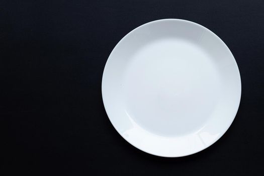 Empty white dish plate on dark background. Top view