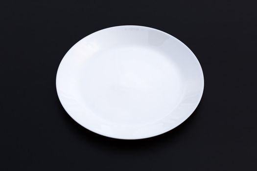 Empty white dish plate on dark background. Copy space