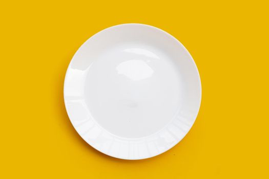 Empty white dish plate on yellow background. 