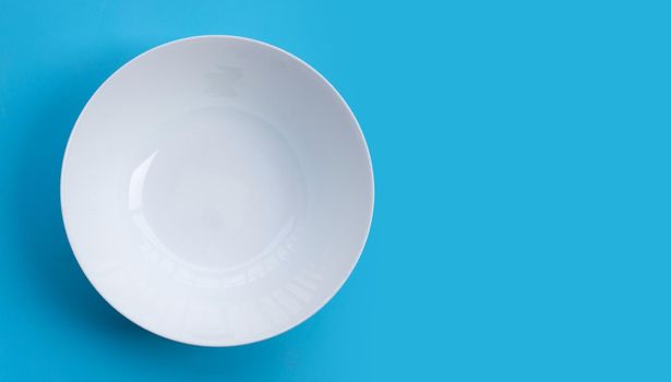 Empty white bowl on blue background.  Top view