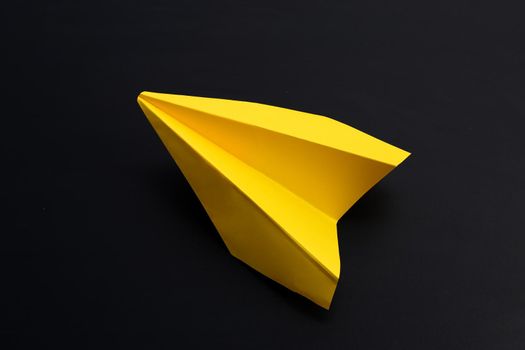 Yellow paper airplane on dark background.