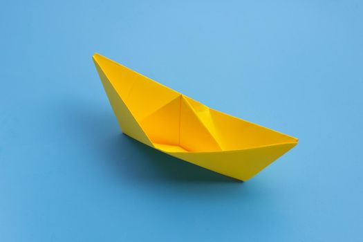  Yellow paper boat on blue background. Copy space